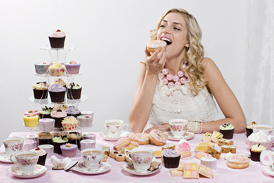 Woman indulging in doughnuts and cakes Photograph by Image Source