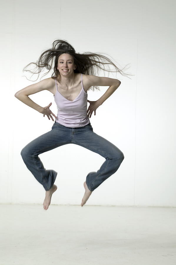 Woman jumping in studio Photograph by Photodisc