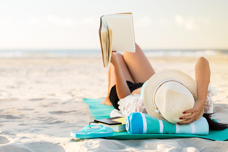Woman lies on the beach reading a book Photograph by Steve Debenport