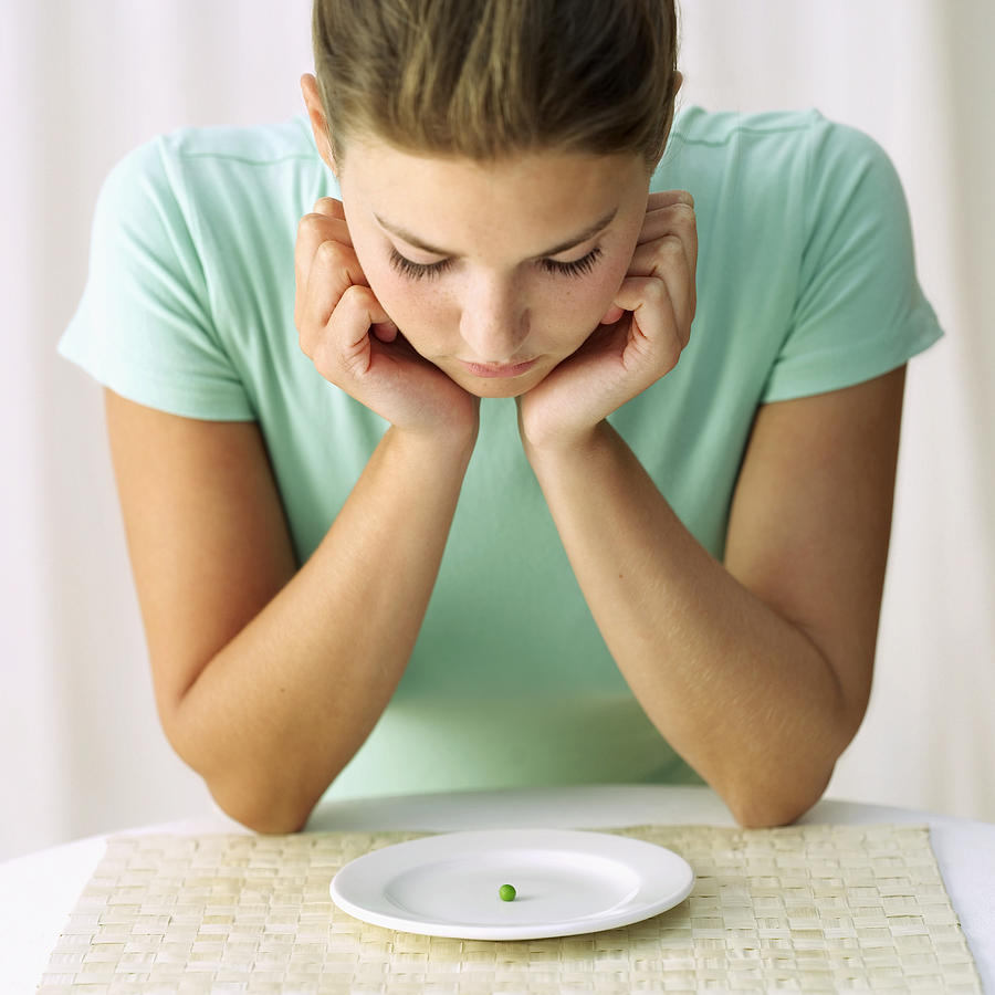 Woman Looking At A Pea On A Plate Photograph by Stockbyte