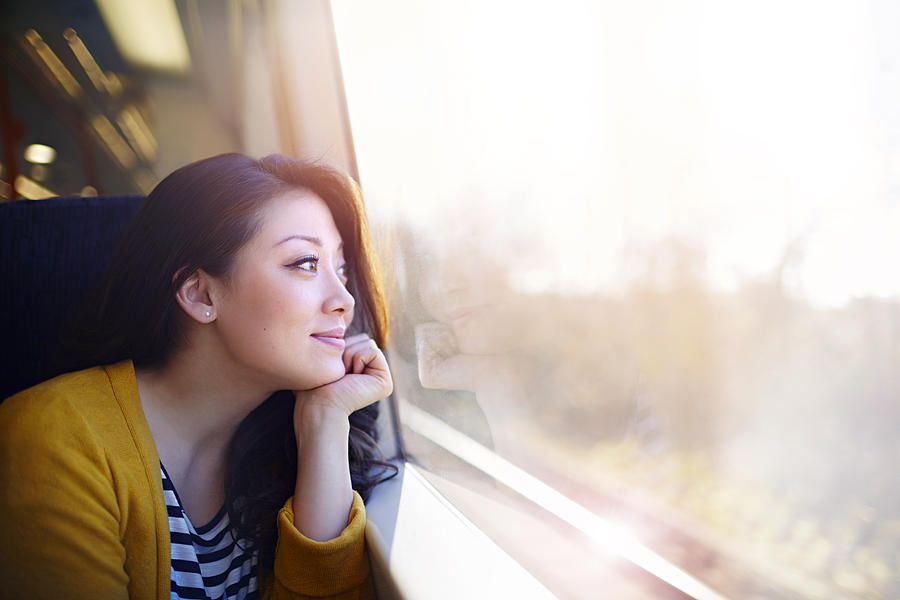 Woman on a train day dreaming out the window. Photograph by Ezra Bailey