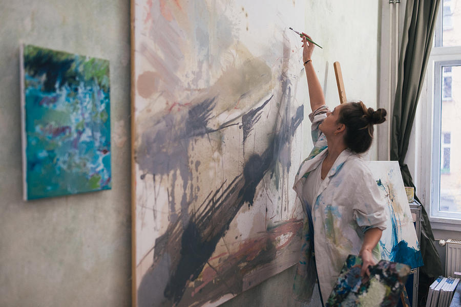 Woman painting a big work in studio. Photograph by Guido Mieth
