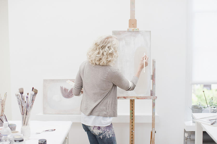 Woman painting on canvas in art studio Photograph by Tom Merton