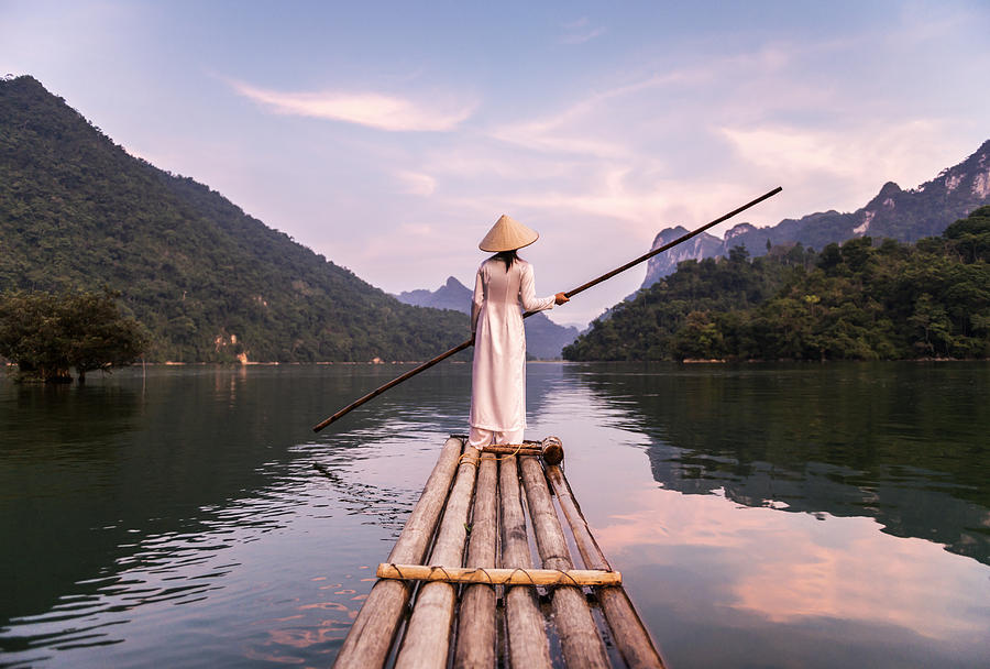 Woman Punting Bamboo Raft Across Lake Photograph by Martin Puddy