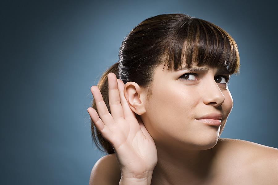 Woman putting hand to her ear Photograph by Image Source