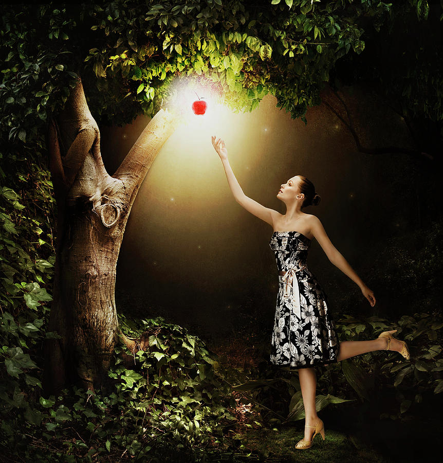 Woman Reaching For Glowing Apple Photograph by Ikon Ikon Images