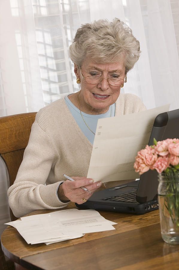 Woman reading and using laptop Photograph by Comstock Images