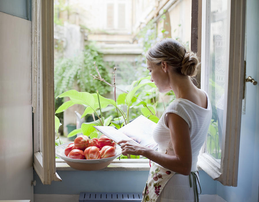 Woman Reading Cookbook At Open Kitchen Window Photograph by Kathrin Ziegler