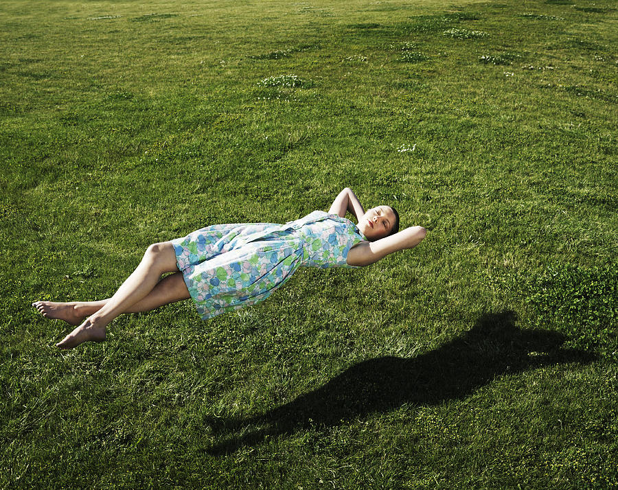 Woman realxing floating above the grass Photograph by Henrik Sorensen