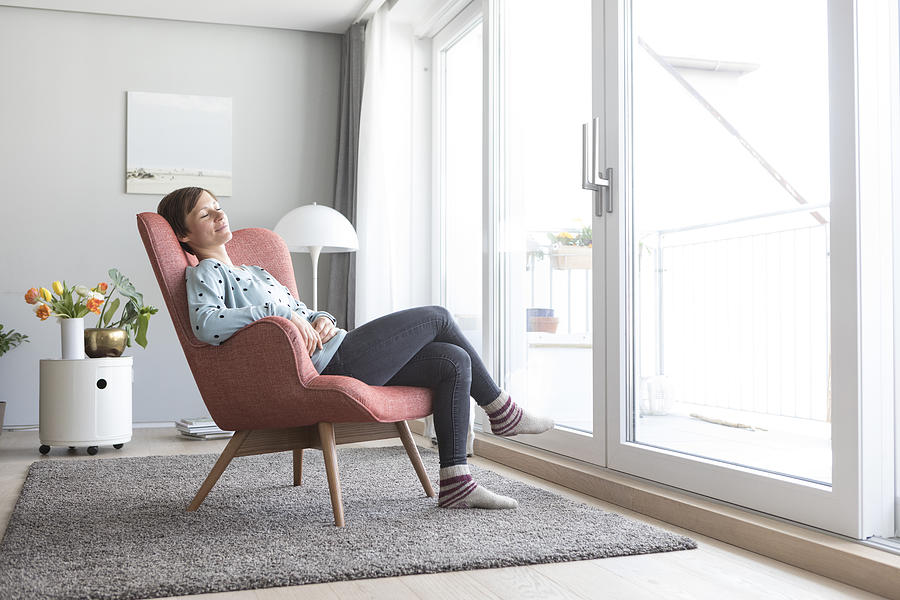 Woman relaxing on armchair at home Photograph by Westend61