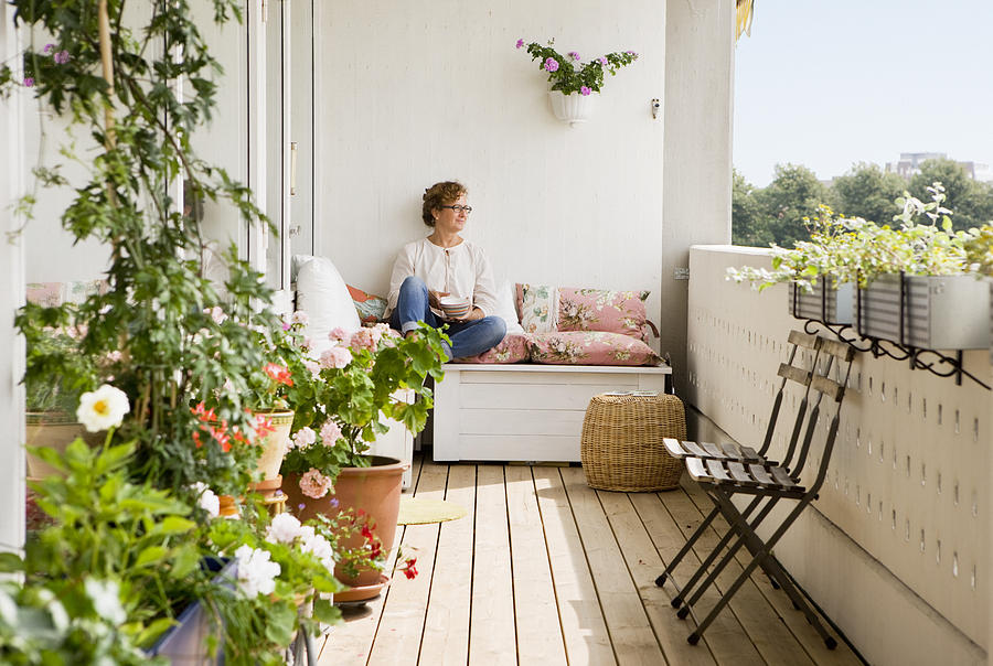 Woman relaxing on balcony Photograph by Johner Images