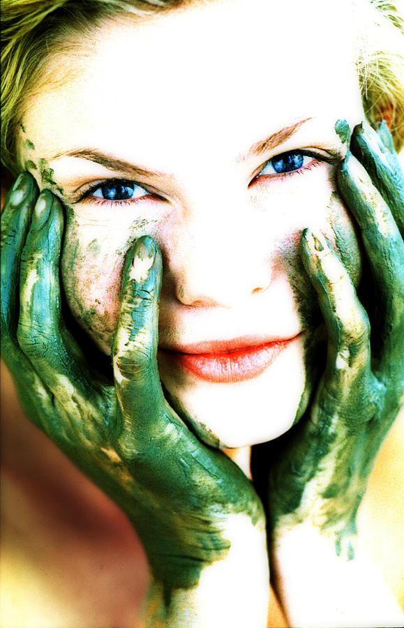 Woman resting head in green painted hands, portrait, close-up Photograph by John Slater