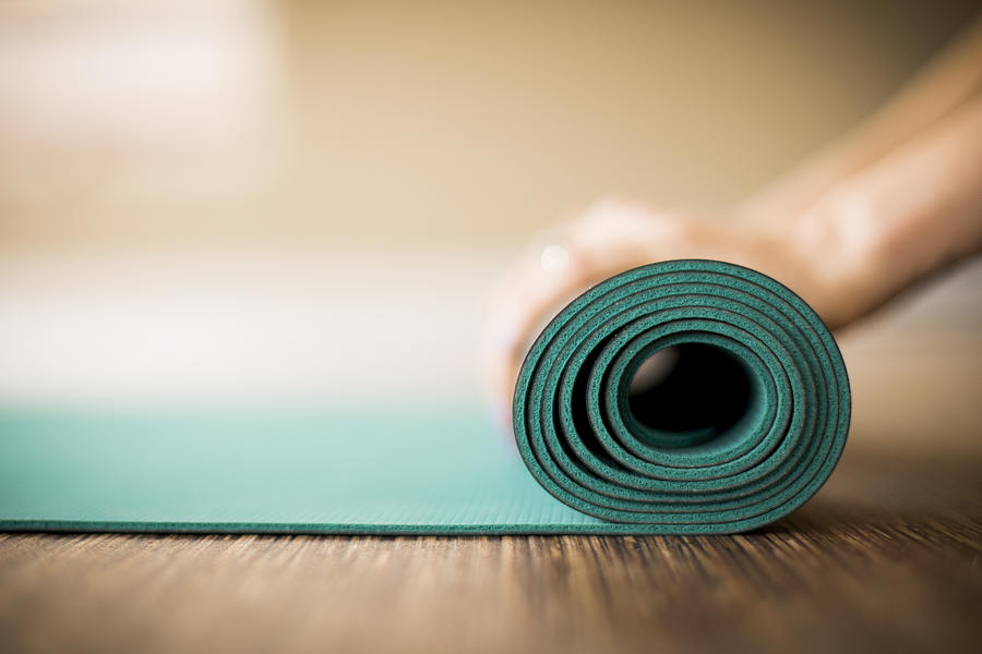 Woman rolling up yoga mat. Photograph by VisualCommunications