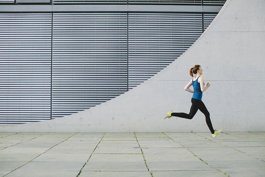 Woman running in front of a building Photograph by Luis Alvarez