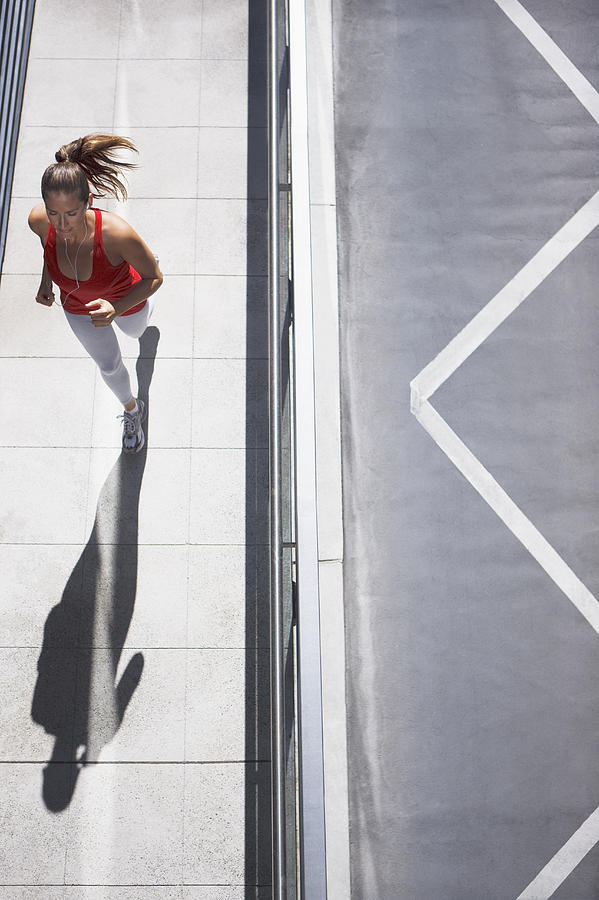 Woman running on urban sidewalk Photograph by Paul Bradbury