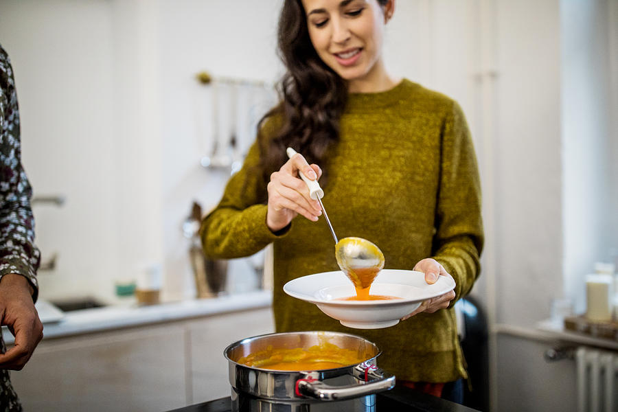 Woman serving squash soup in bowl during dinner party Photograph by Luis Alvarez