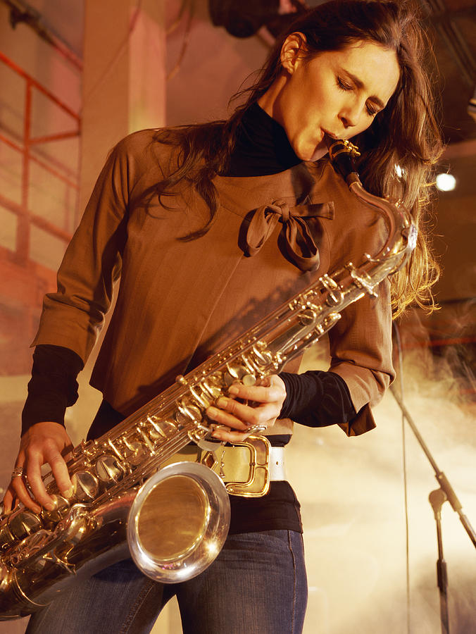 Woman Stands on a Smoky Stage Playing a Saxophone With Passion Photograph by Digital Vision.