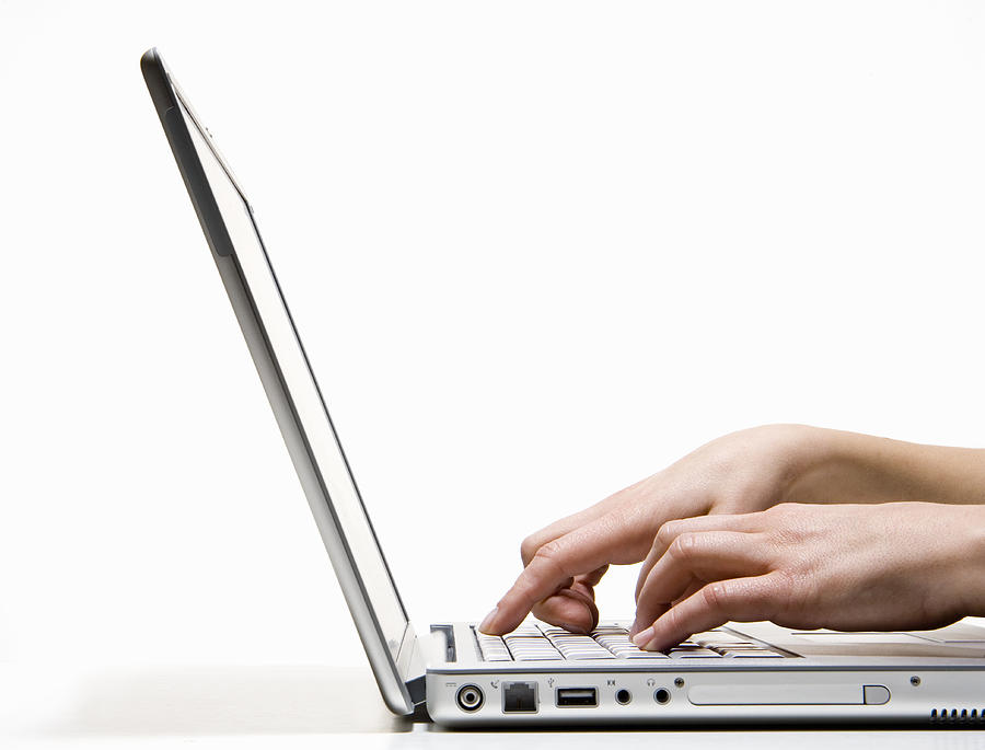 Woman using laptop, side view, close-up Photograph by PM Images