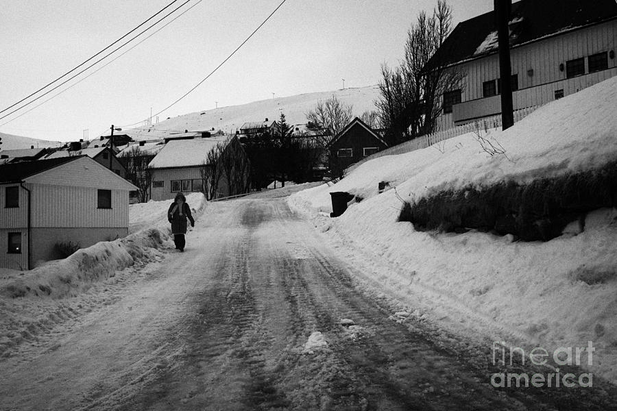 Winter Photograph - woman walking down steep ice covered street in Honningsvag finnmark norway europe by Joe Fox