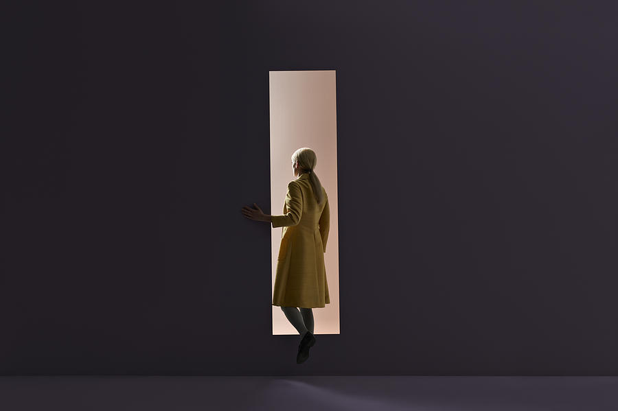 Woman walking into rectangular opening in coloured wall Photograph by Klaus Vedfelt
