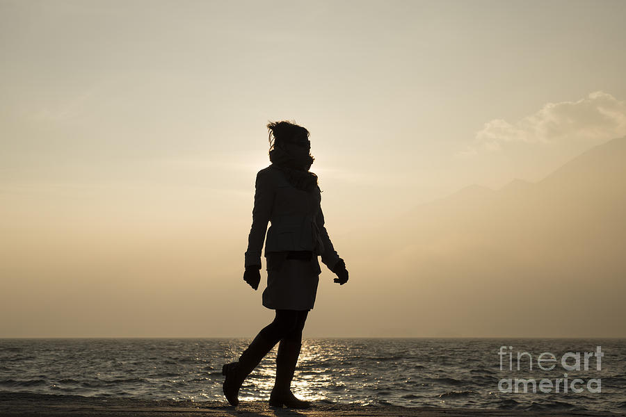 Sunset Photograph - Woman walking on the lake front by Mats Silvan