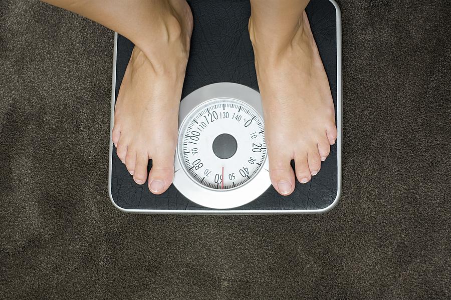 Woman weighing herself Photograph by Image Source