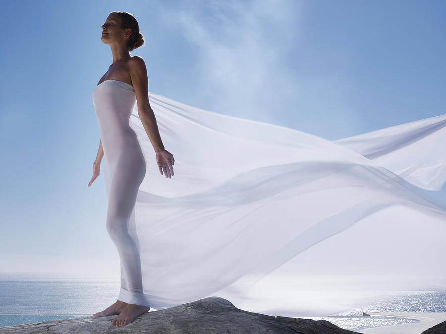 Woman with a sheer sheet with ocean backdrop Photograph by OJO Images