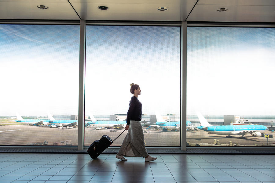 Woman with suitcase is going to board on the next flight Photograph by Drazen_