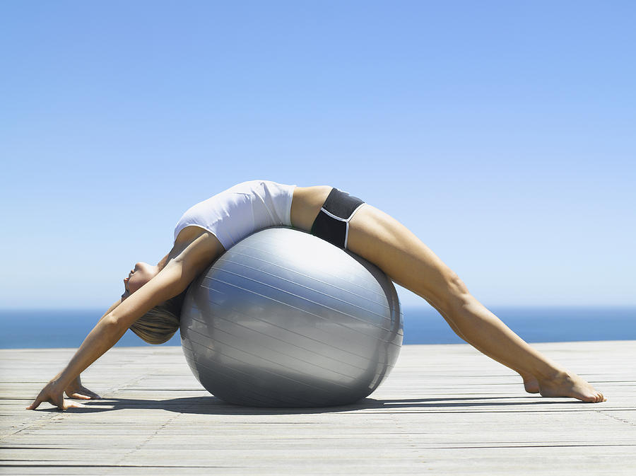 Woman working out with an exercise ball Photograph by OJO Images