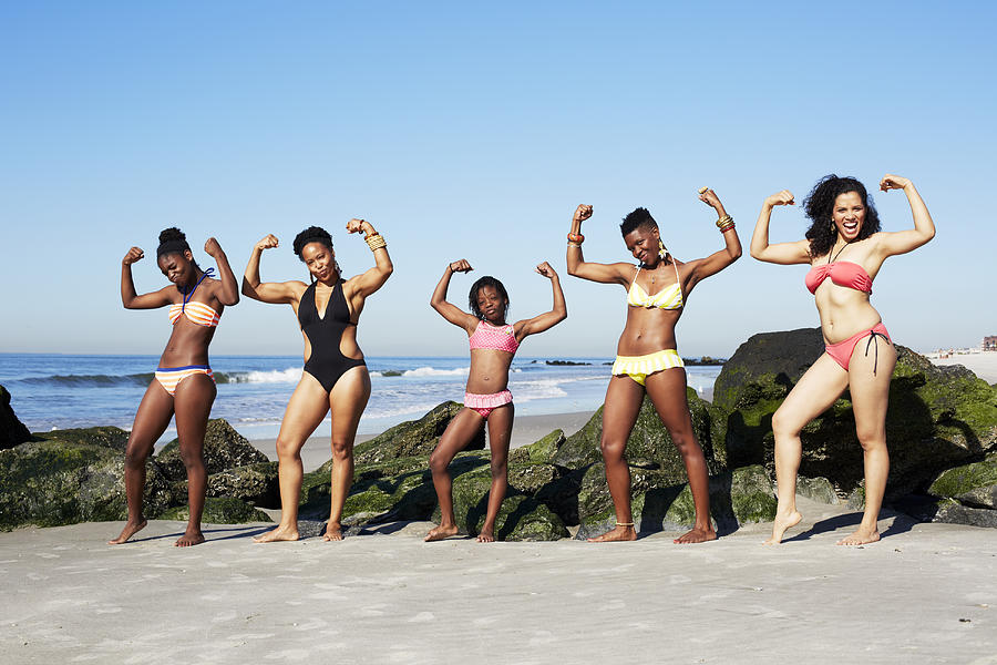 Women flexing muscles on beach Photograph by Blend Images/Granger Wootz