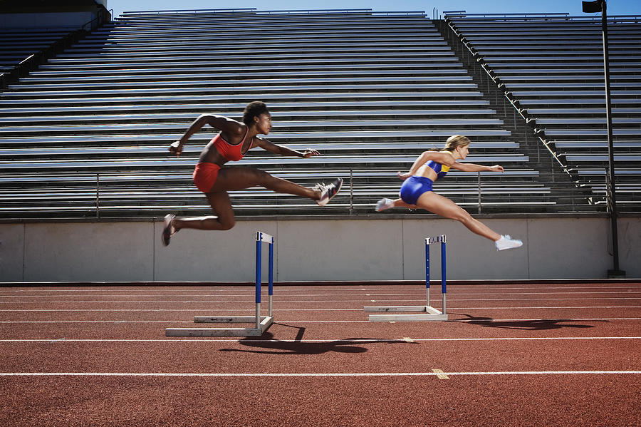 Women jumping over hurdles Photograph by Jupiterimages