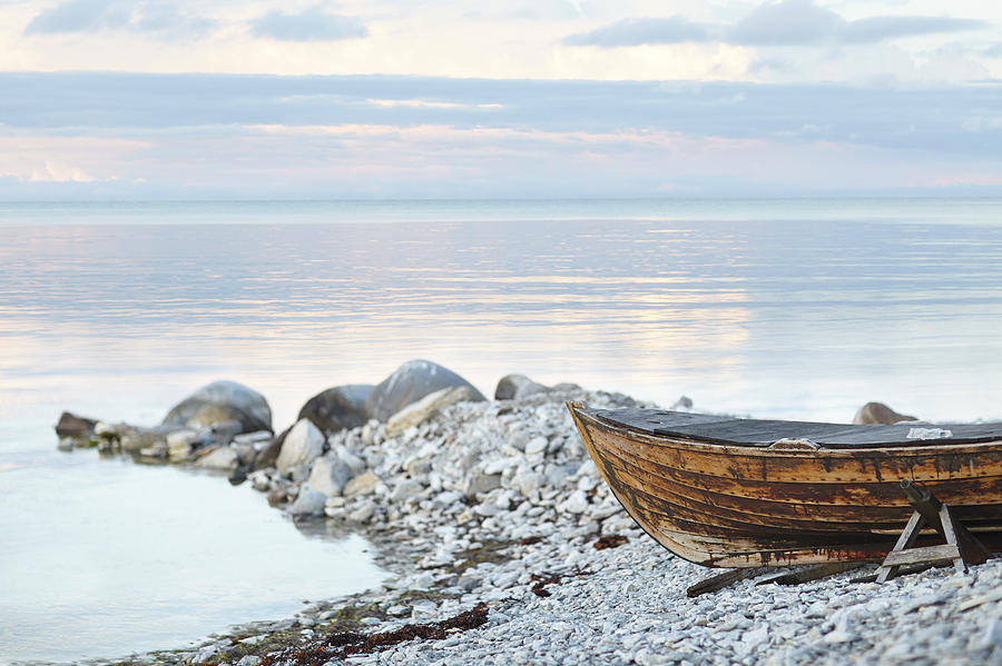 Wooden boat on rocky coast Photograph by Johner Images