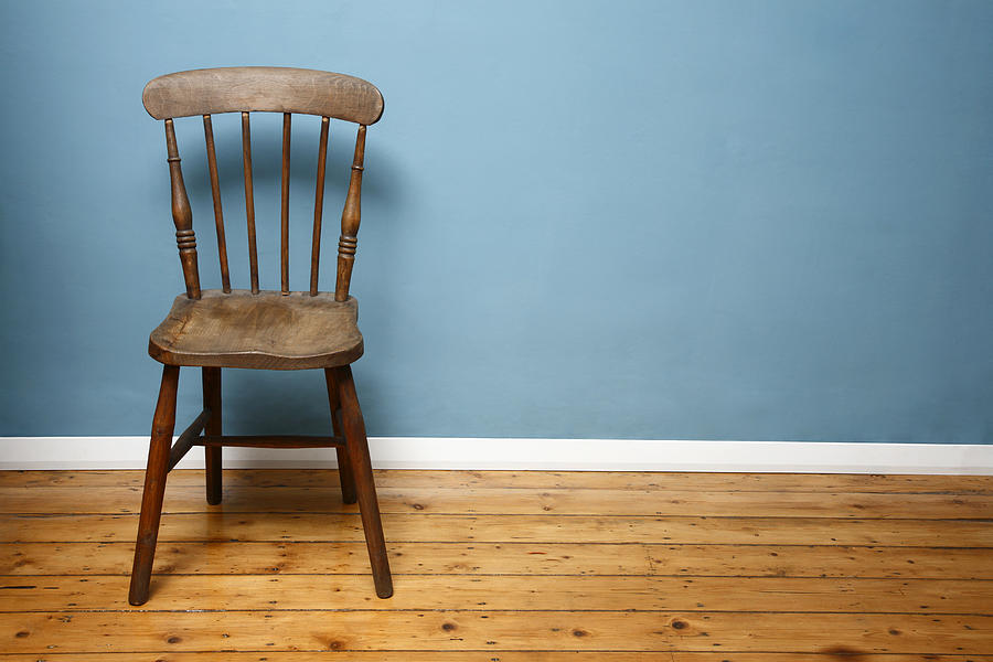 Wooden chair against a blue wall in an empty room Photograph by Julian Ward