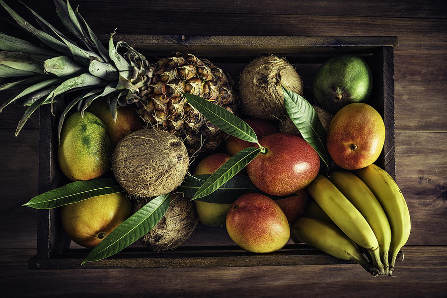Wooden crates with assorted tropical fruits in rustic kitchen. Natural lighting Photograph by Apomares