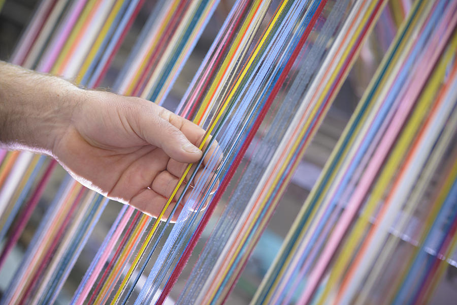 Worker adjusting multicoloured silk yarn on industrial loom in textile mill Photograph by Monty Rakusen