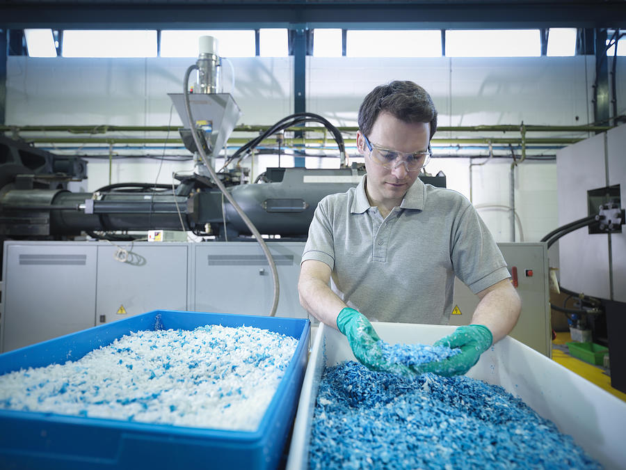 Worker inspecting recycled plastic in plastics factory Photograph by Monty Rakusen
