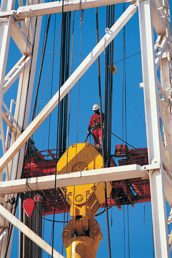 Worker on oil rig crane Photograph by Photodisc