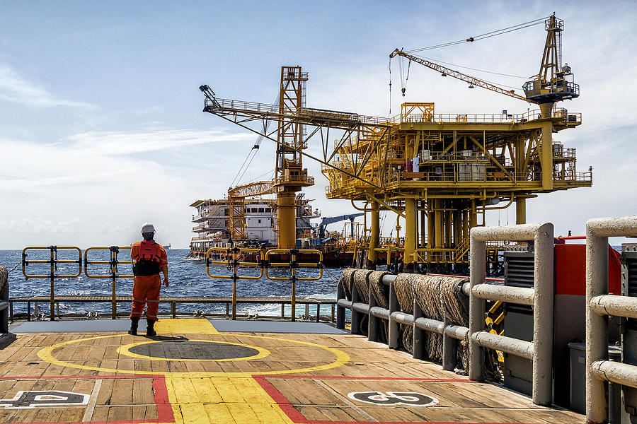 Worker on the boat look at Oil and gas industrial platform in the gulf or the sea, The world energy of oil and gas company, Offshore oil and rig construction. Industry concept. Photograph by Chain45154