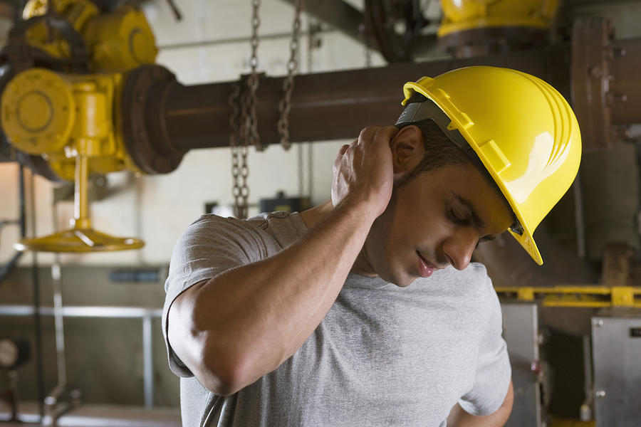 Worker wearing hardhat and experiencing neck pain Photograph by Thinkstock Images