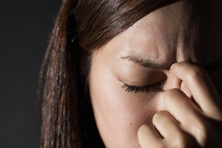 Worried woman rubbing her forehead Photograph by Yuichiro Chino