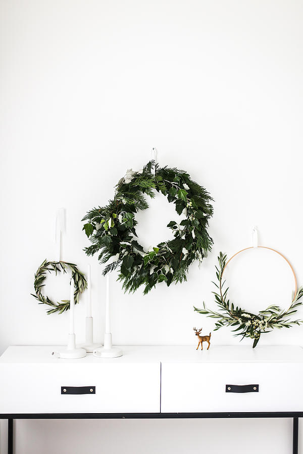Wreaths hanging on a wall by a sideboard Photograph by Emmaduckworth