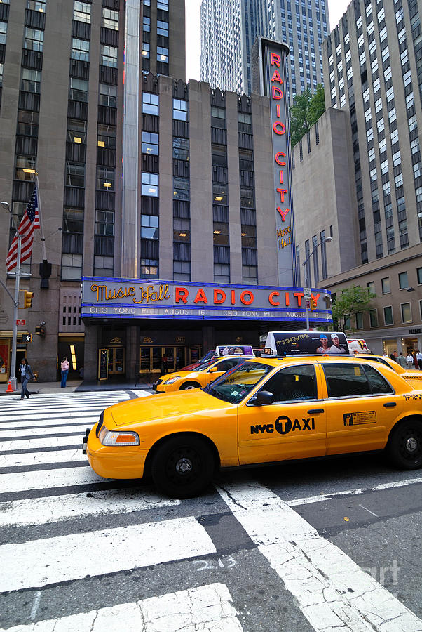 Yellow Cabs pass in front of Radio City Music Hall Photograph by Amy Cicconi
