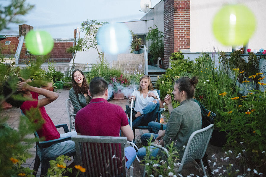 young adults, roof garden, talking, smoking Hookah Photograph by Fotografixx