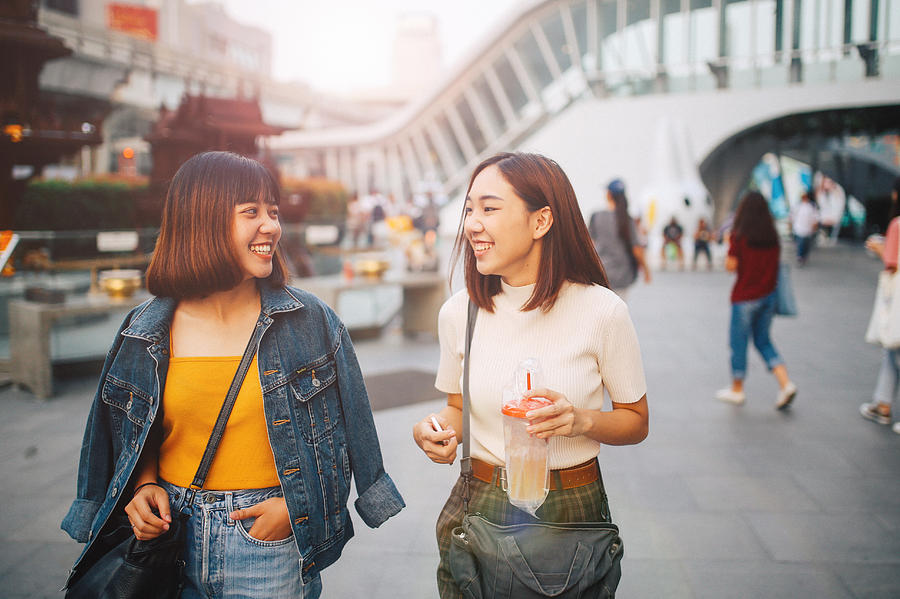 Young Asian women walking in Bangkok, going shopping together, chatting Photograph by Lechatnoir
