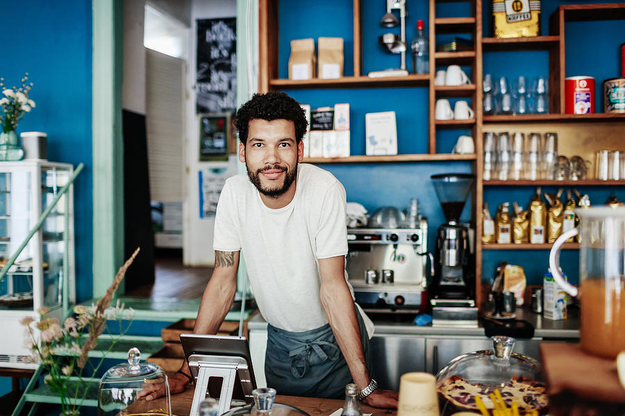 Young Barista Smiling Leaning On Coffee Shop Counter Photograph by Tom Werner