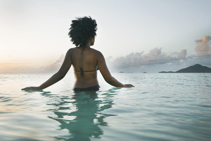 Young black woman wading into ocean, rear view. Photograph by Gary John Norman