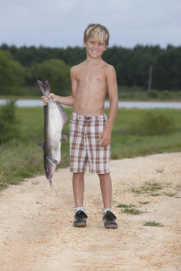 Young Boy Holding a Fish Next to River Photograph by Sean Murphy
