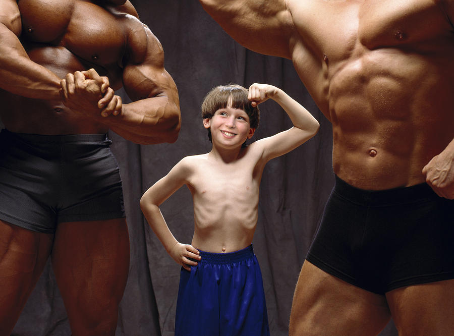 Young boy making muscles with body builders. Photograph by Howard Berman
