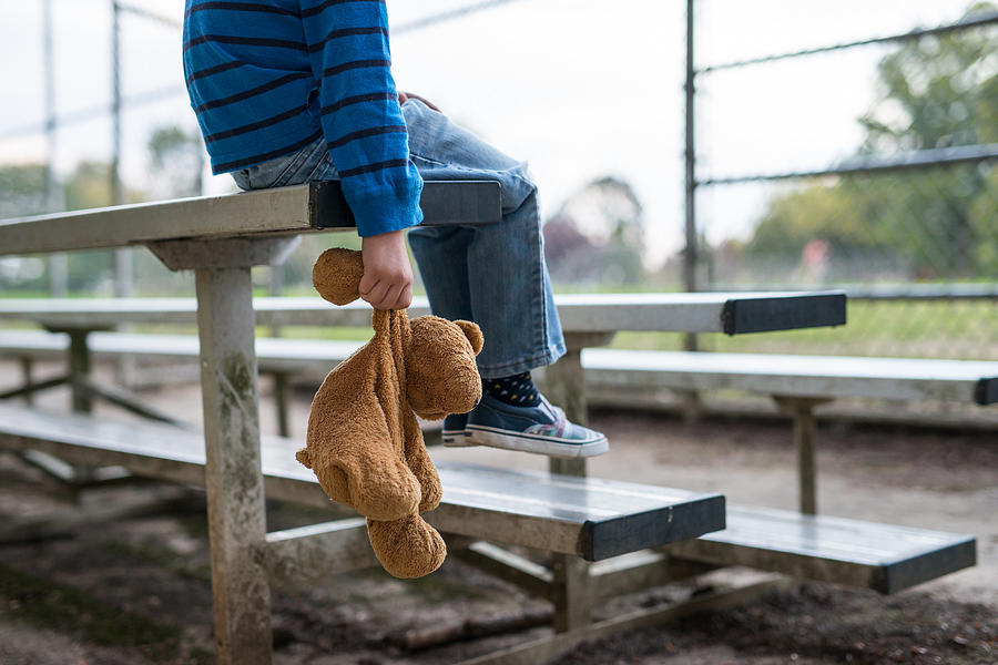 Young boy sitting by himself on on bleachers. Photograph by FatCamera Young boy sitting by himself on on bleachers. Photograph by FatCamera