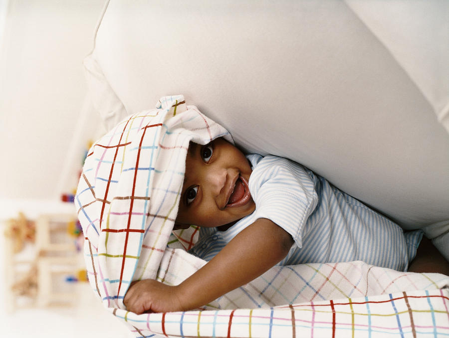 Young Boy Sitting on a Chair and Playing Under a Sheet Photograph by Digital Vision.